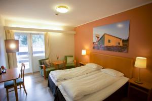 克维内斯达尔Utsikten Hotell Kvinesdal的配有一张床、一张桌子和一张桌子的酒店客房