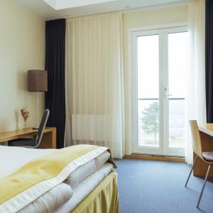 克维内斯达尔Utsikten Hotell Kvinesdal的配有一张床、一张书桌和一扇窗户的酒店客房