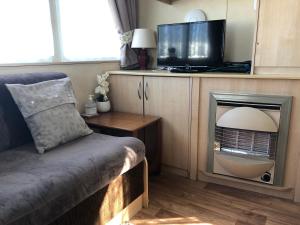 伯克顿Norfolk Lavender Caravan - Sleeps 4 - WiFi and Sky TV Included的客厅配有电视、沙发和电视。