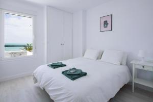 奇克拉纳－德拉弗龙特拉Dulce Barrosa Mar Beach Front的白色的卧室设有白色的床和窗户。