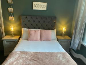 卡迪夫Inn Cardiff的一间卧室配有一张带粉色枕头的床和两盏灯。