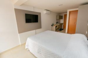 若昂佩索阿Manaíra Apart Flat的卧室配有白色的床和平面电视。
