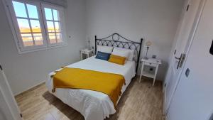San PedroLa Casita del Arco Ático的一间卧室配有一张带黄白色床单的床和窗户。