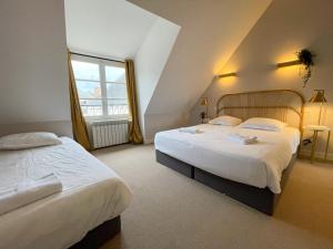圣艾尼昂Maison des fleurs的酒店客房设有两张床和窗户。