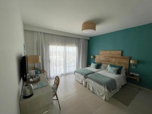 桑坦德利亚湾Hotel Playa Santandria Adults Only的一间卧室配有两张床和一张书桌及电视