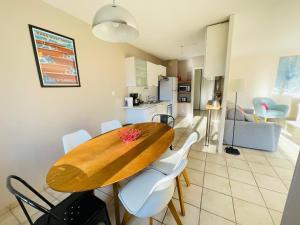 安锡Bel appart tout confort的厨房以及带木桌和白色椅子的用餐室。