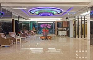 番路乡仁义湖岸大酒店的大堂设有大型紫色天花板,配有椅子和鲜花