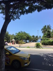 芽庄VINH MINH HOTEL的停在街道上树旁的黄色汽车