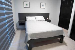 恩塞纳达港Clean&Equipped, 1-Floor 3-Bedroom Downtown House的一间卧室配有一张带白色床罩的大床