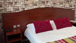 莫尔莱The Originals City, Hôtel Fontaine, Morlaix的一张带红色枕头和木制床头板的床