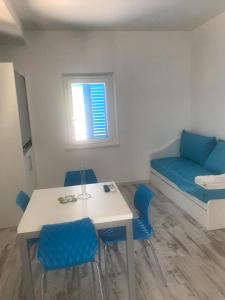努马纳Casabianca Appartamenti的配有桌子、蓝色椅子和床的房间