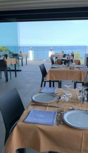 卡拉古诺内Hotel L'Oasi的一间设有桌椅的海景餐厅