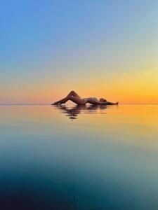 斯韦蒂·斯特凡Vivid Blue Serenity Resort的日落时分躺在水中的女人