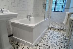 威灵顿Worlington Hall的白色的浴室设有浴缸和水槽。