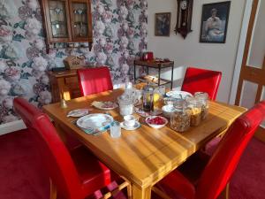 大雅茅斯Bastwick House B&B的一张木桌,四周摆放着红色椅子,上面有食物
