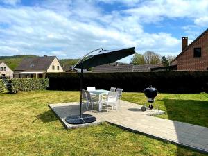昂内Gîte au 14 - au calme avec jardin , proche de Dinant的天井配有桌子、遮阳伞和烧烤架。