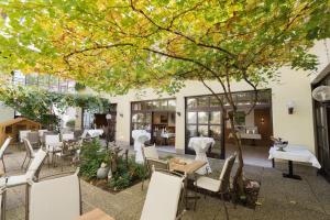 德意志兰茨贝格格斯夫 - 科拉尔国际餐厅酒店的庭院配有白色的桌椅和一棵树
