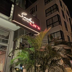 曼谷Sacha's Hotel Uno SHA的建筑前的酒店标志和棕榈树