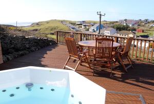 杜林Luxury Lodges in Doolin Village with Hot Tubs的一个带桌椅的甲板和一个热水浴缸