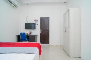 班贾尔马辛RedDoorz Syariah near Jalan A Yani KM 8 Citraland的一间卧室配有一张床、一张书桌和一台电视。