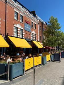 南安普敦白星客栈的一条街上,人们坐在桌子上,拿着黄色的雨伞