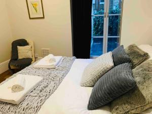 伦敦Luxury Fulham Flat with 5* touches nr River Thames的卧室配有带枕头的床铺和窗户。