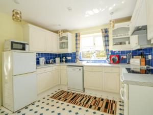 盖顿The Granary Cottage的厨房配有白色橱柜和 ⁇ 格地板