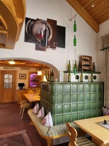 托特瑙Hotel Obergfell的餐厅设有绿色长凳、桌子和葡萄酒瓶
