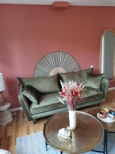 欧赖* LE CHAMARELLE * Hyper Centre Auray *的客厅设有绿色沙发和带鲜花的桌子