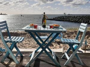 艾默伊登Beachhouse direct aan zee的一张野餐桌,配有一瓶葡萄酒和两把椅子
