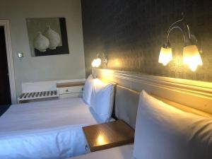 德比The Continental Hotel, Derby的酒店客房,设有两张床,墙上有灯