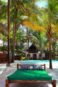 布韦朱Zanzibar Gem Beach Bungalows的棕榈树海滩上的一张床位和一个游泳池