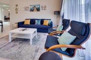 迪拜Shoreline The Palm, Free beach & pool access的客厅配有蓝色的沙发和椅子