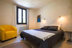 尼姆Maison dans les Arbres, SPA, Tennis, Parking的一间卧室配有一张床和一张黄色椅子