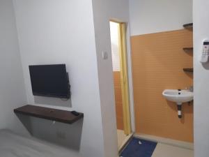 巴淡岛中心Rooms at Josapa Guest House的一间带水槽的浴室和墙上的电视