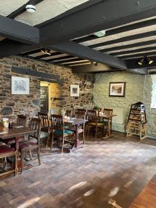 欧克汉普敦The Fountain Inn & Riverside Restaurant的一间设有木桌和椅子的餐厅以及石墙