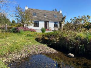 SkeabostTaigh Iain Mhòir的前面有一条河的房子