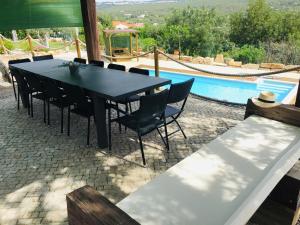 埃斯托伊Villa Monte da Alfarrobeira的游泳池旁的一张黑桌子和椅子