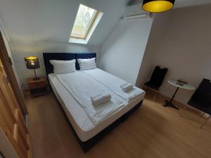 塞格德Palma Vendégház的一间卧室配有一张带白色床单的床和一扇窗户。