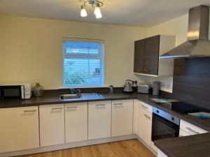 威廉堡Corran, Glenloch View, Fort William 2-Bedroom Loch Side Flat的厨房配有白色橱柜、水槽和窗户。