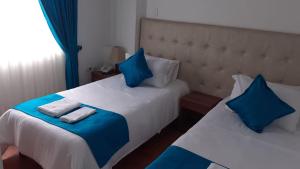 波哥大Hotel en Bogota - Fontana Di Trevi的一间卧室配有两张带蓝白色枕头的床