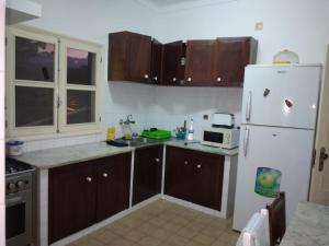 圣多美Santos`s House的厨房配有木制橱柜和白色冰箱。