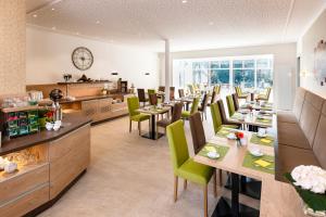 莱尔特Landhotel Behre的餐厅设有木桌和绿色椅子