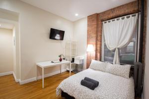 纽约一卧室超级公寓的一间卧室配有一张床、一张桌子和一个窗户。