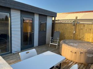 GufunesAdorable Tiny House in Reykjavik的露台设有热水浴池和甲板上的椅子
