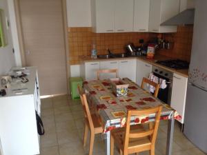 马尔扎梅米Holiday Home Residence Azzurro的一间带桌椅的厨房和一间带白色橱柜的厨房