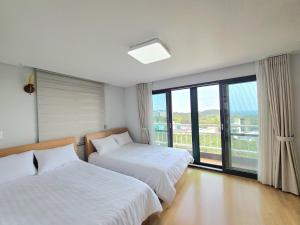 西归浦市赫拉卡斯尔度假屋的一间卧室设有两张床和大窗户