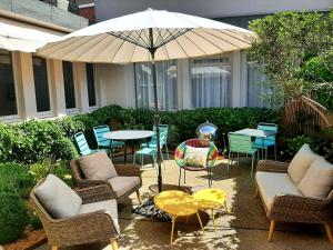 圣弗卢尔Cit'Hotel Grand Hotel L'Etape的庭院配有椅子和桌子及遮阳伞