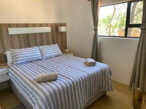 贝拉贝拉Vlakkieskraal Farmstay - BushBaby House的一间卧室配有一张带条纹毯子的床和窗户