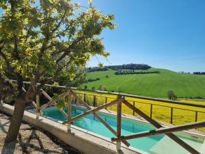洛雷托B&B Ceresà - Country House的木栅栏和田野旁边的游泳池